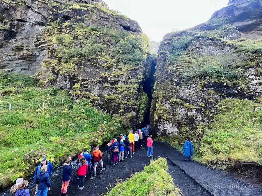 A line of people waiting to enter a cave.