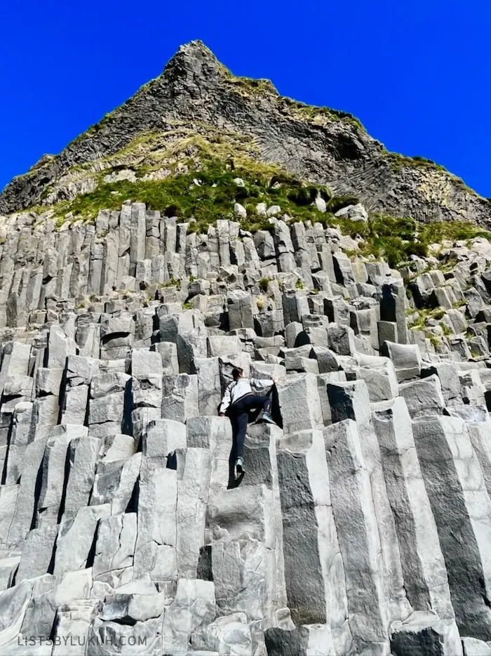 A woman climbing up a stack of rocks.