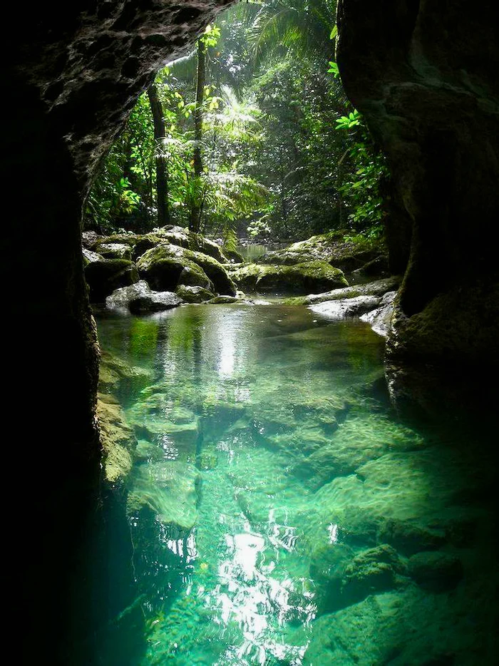 The exit of a cave with clear water.
