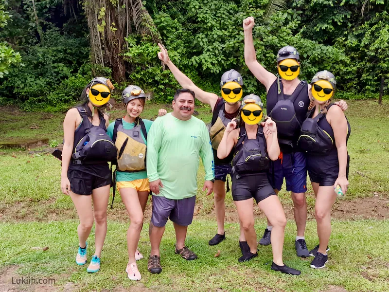 A group of seven people wearing helmets, water shoes, and life jackets.
