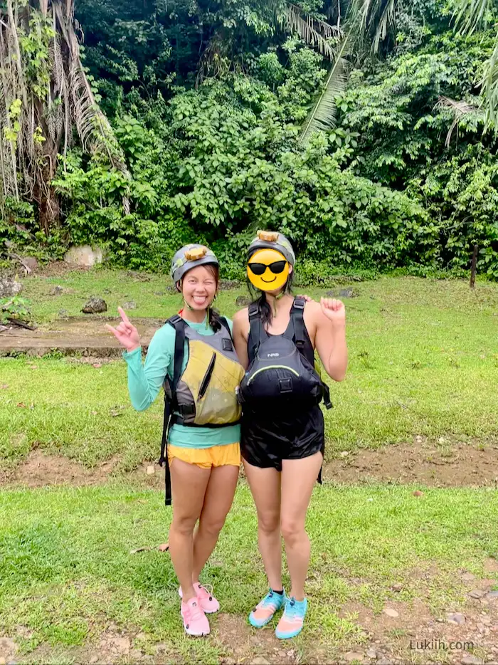 Two women wearing helmets, life vests, and water shoes.