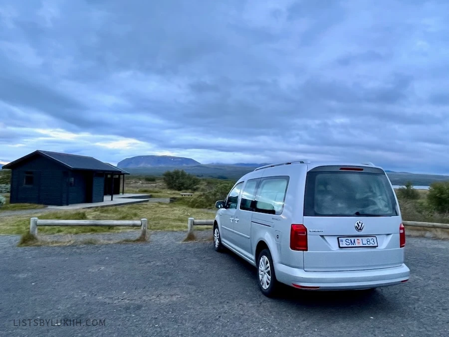 A gray campervan parked at an isolated flat campsite.