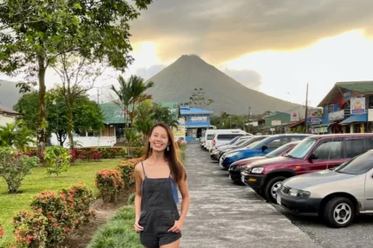 A woman standing in a street with the silhouette of a volcano in the background.