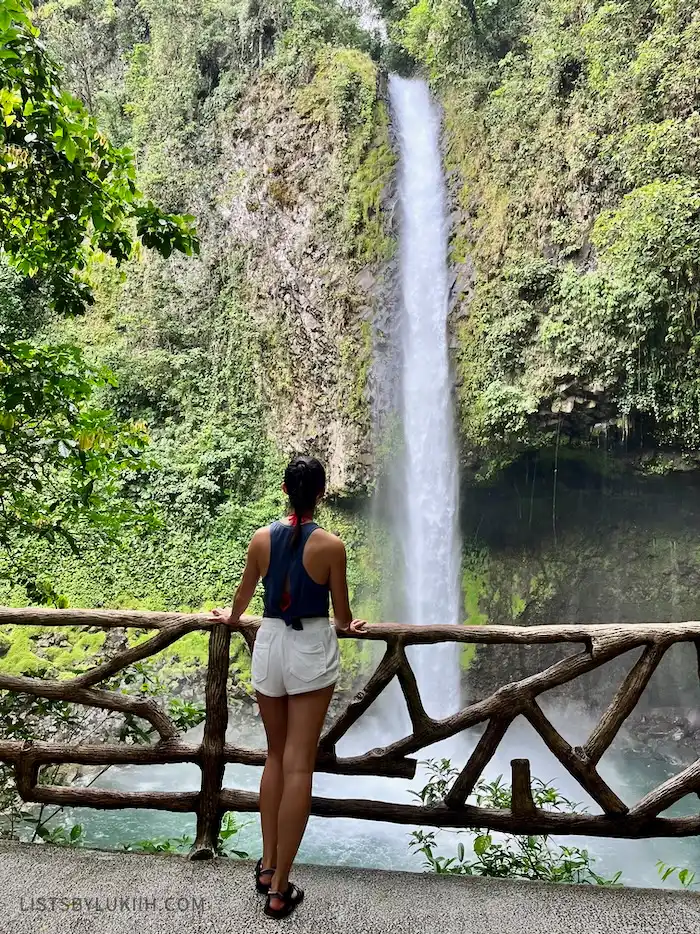 A woman standing on a platform looking at a waterfall.