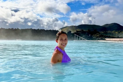 A woman partially submerged in an outdoor pool with milky blue water.