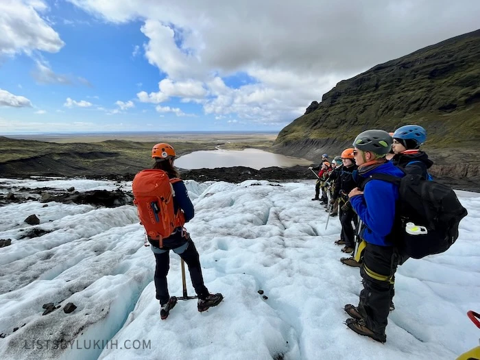 A group of people with gold gear standing on a glacier.