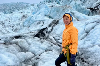 A woman wearing cold gear and hiking on a glacier, surrounded by ice in all directions.