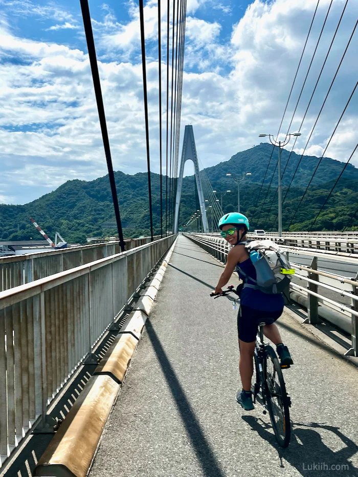 A woman on a bike crossing a long bridge.