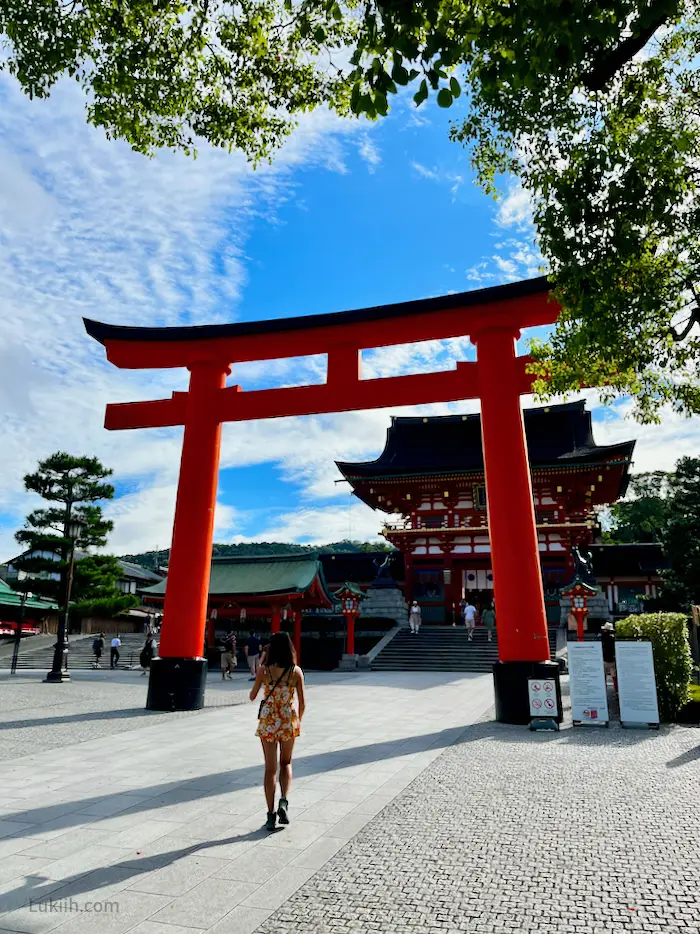 A woman approaching a giant red torii gate.