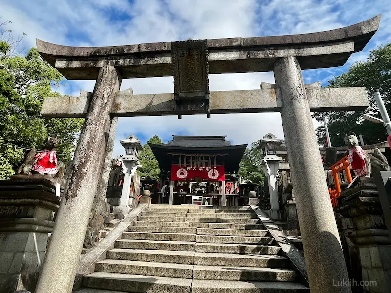 A torii gate made of stones with more shrines behind it.