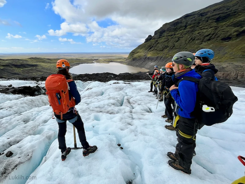 A group of people with gold gear standing on a glacier.