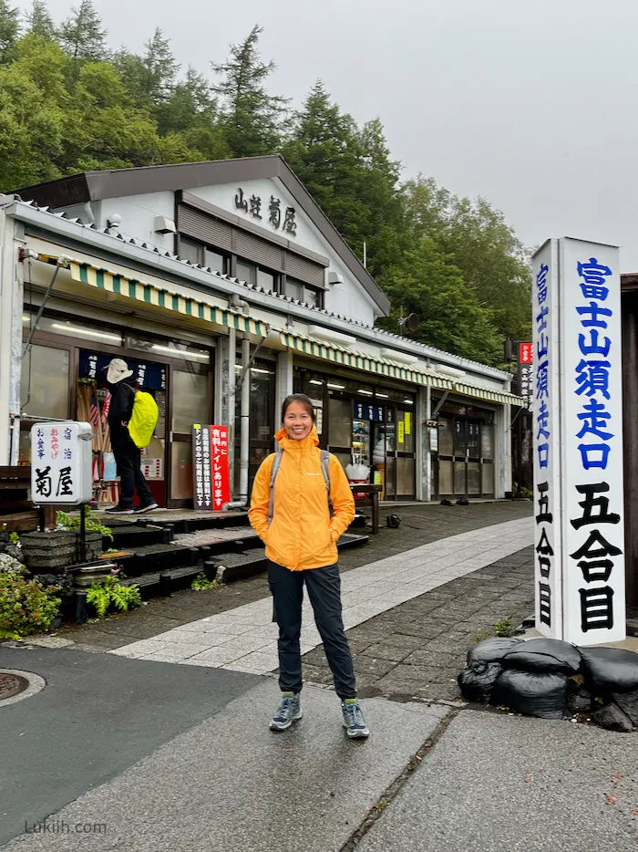 A hiker standing in front of a shop with Japanese letters on it.