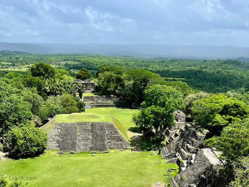 A view from high-above looking down at a green, lush jungle with stone ruins in the open area.