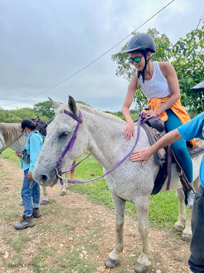 A woman riding and petting a horse.