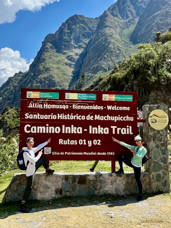 Two hikers pointing at a sign that says Welcome and Inca Trail.