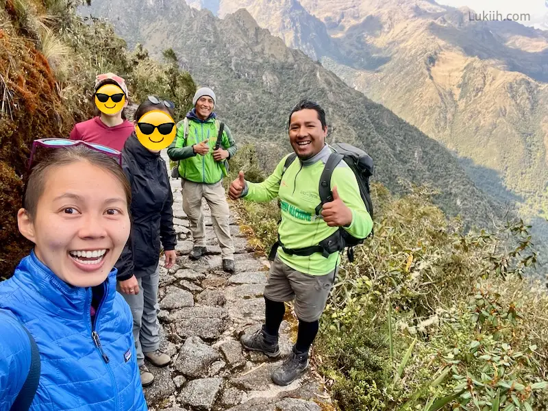 A group of people posing for a selfie while on a mountain trail.