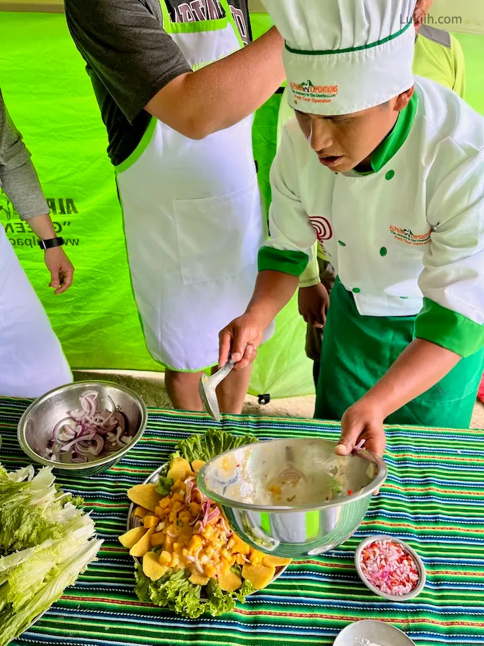 A man in a chef hat serving mango salad.