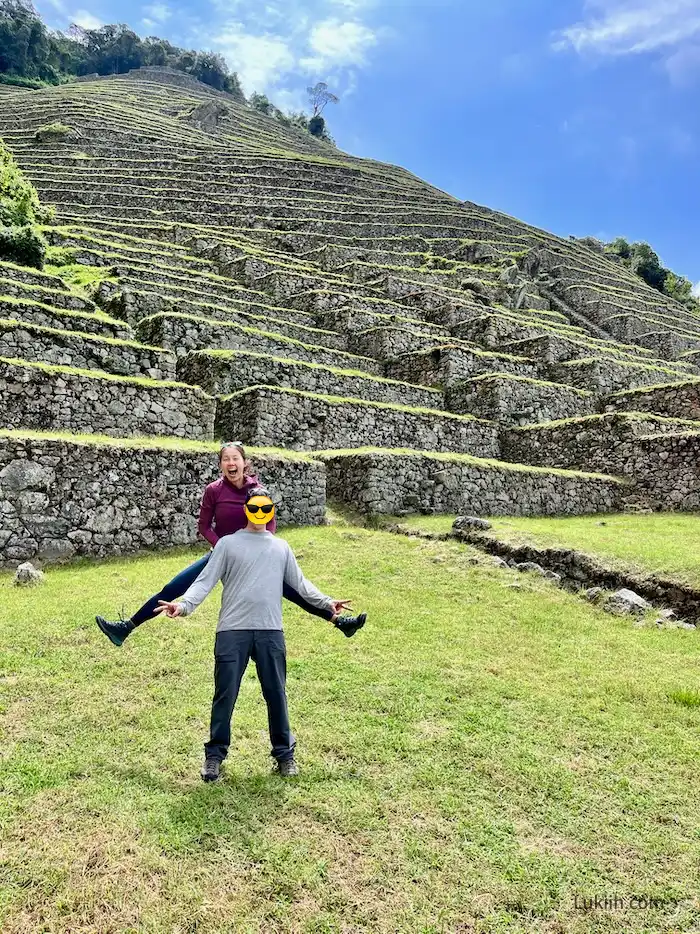Two people standing in front of ancient terraces with grass.