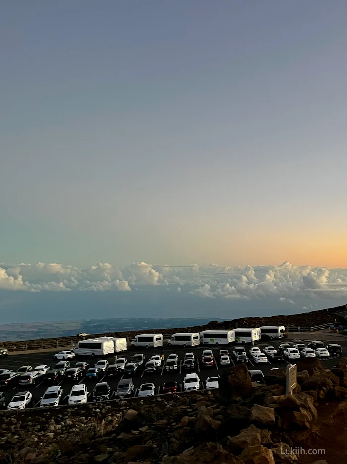 A parking lot full with vehicles, on top of a mountain.