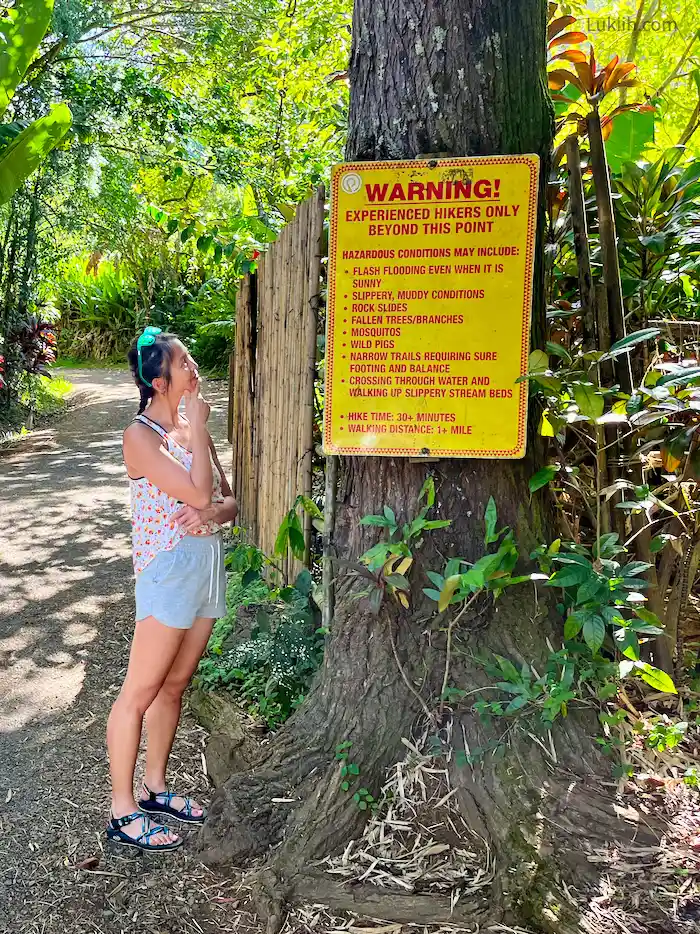 A woman standing on a trail looking at a sign warning about bugs.
