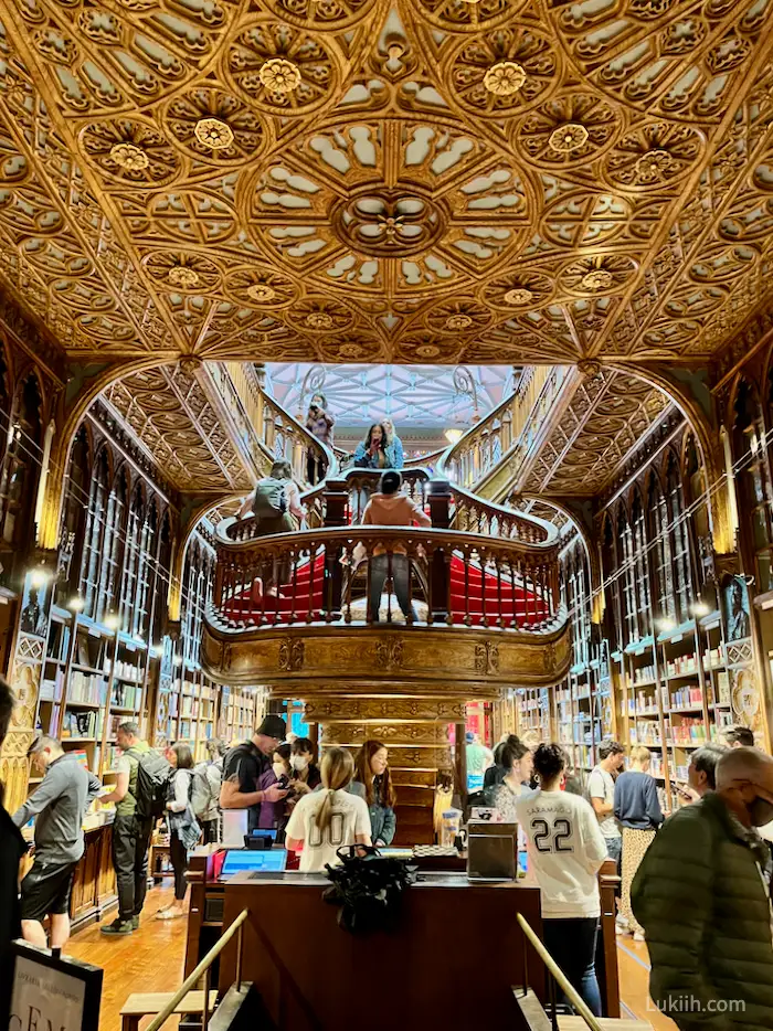 The interior of an intricate bookstore with a golden staircase and ceiling.