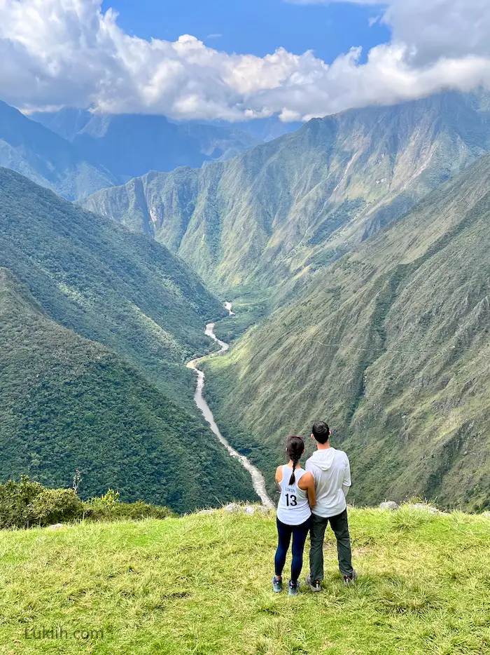 Two people standing and facing a vast valley.