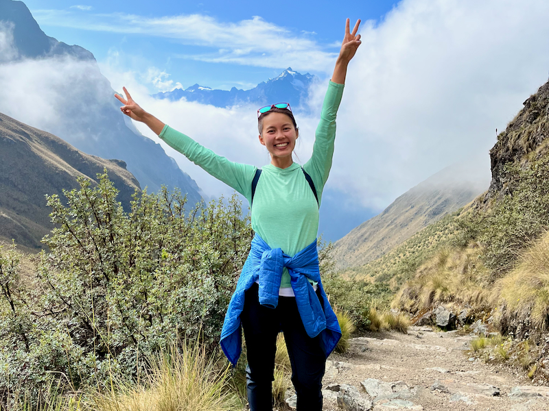 A woman hiker posing in front of a stunning mountain view.