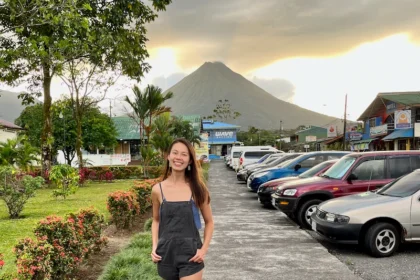 A woman standing in a street with the silhouette of a volcano in the background.