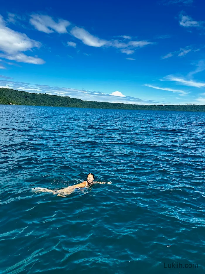 A woman swimming in a clear blue lake water.