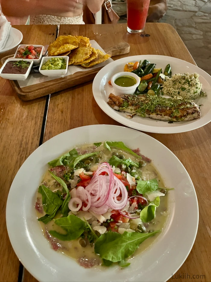 Plates of food with salad, fish, and plantain chips.