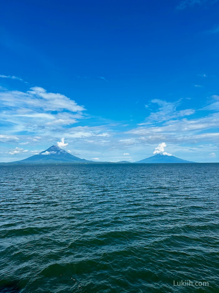 Two volcanos in the distance surrounded by ocean.