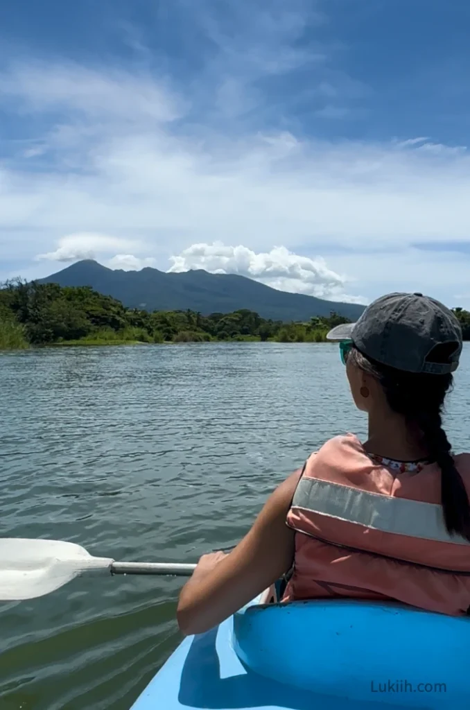 A person kayaking and look out a volcano in the distance.