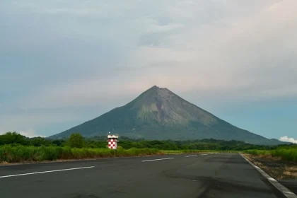 A road extending into the background with a towering volcano.