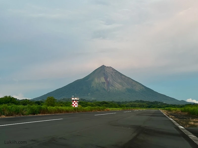 A road extending into the background with a towering volcano.