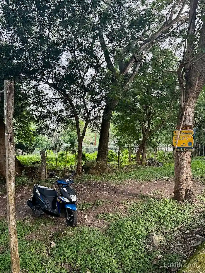 A scooter parked on a dirt road surrounded by trees.