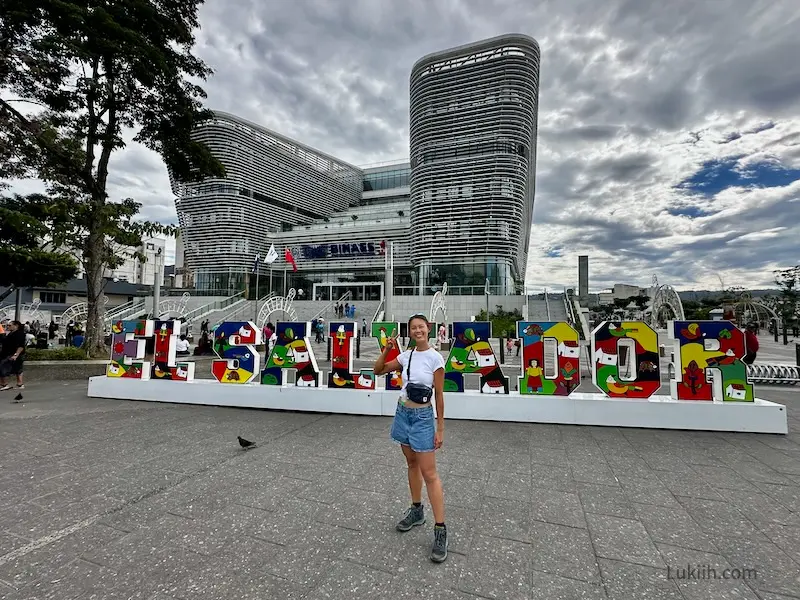 A woman standing in front of a sign that says El Salvador.