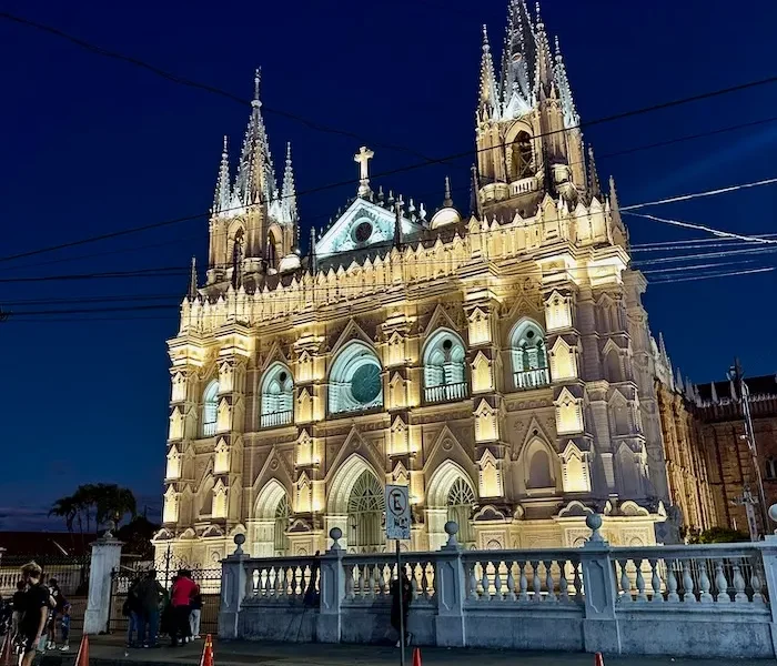 A lit-up ornate white church at night.