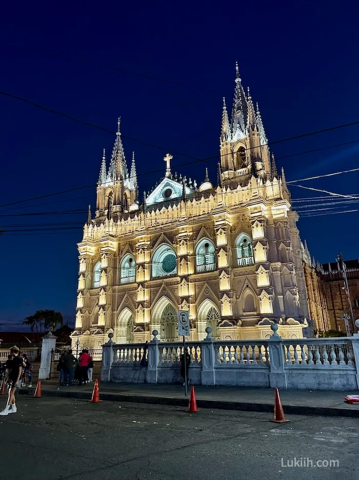 A lit-up ornate white church at night.