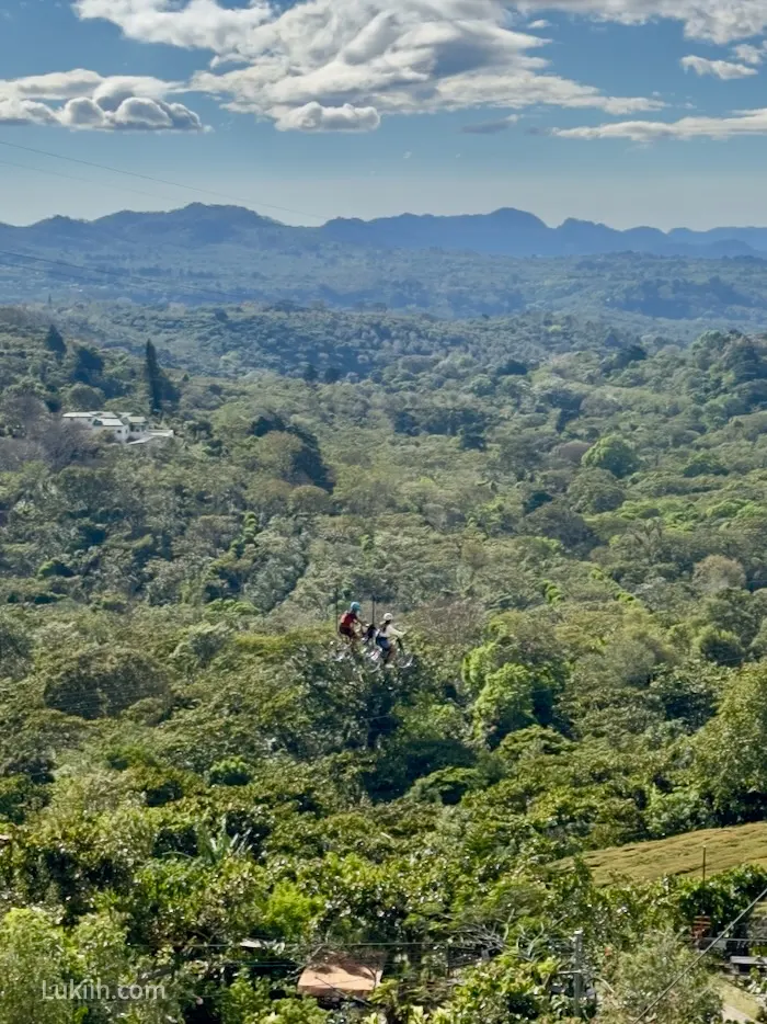 Two people riding bikes on a zipline.