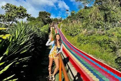 A woman standing next to a big rainbow slide.