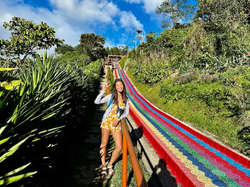 A woman standing next to a big rainbow slide.