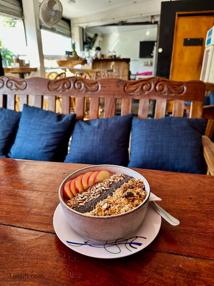 A bowl of smoothie with apple, seeds and granola.