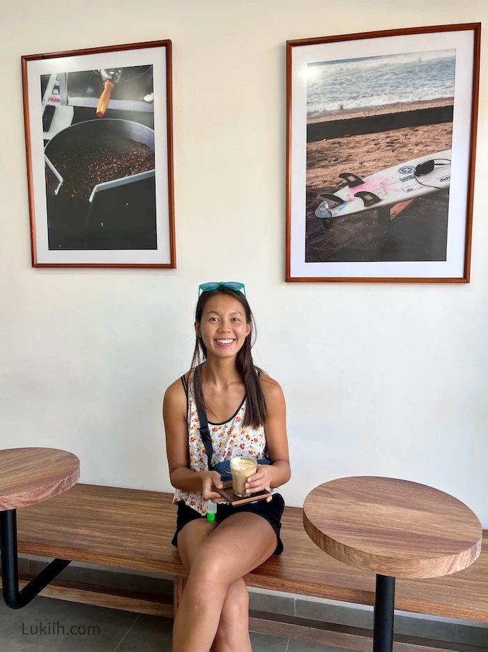 A woman sitting on modern wood furniture holding a cappuccino.