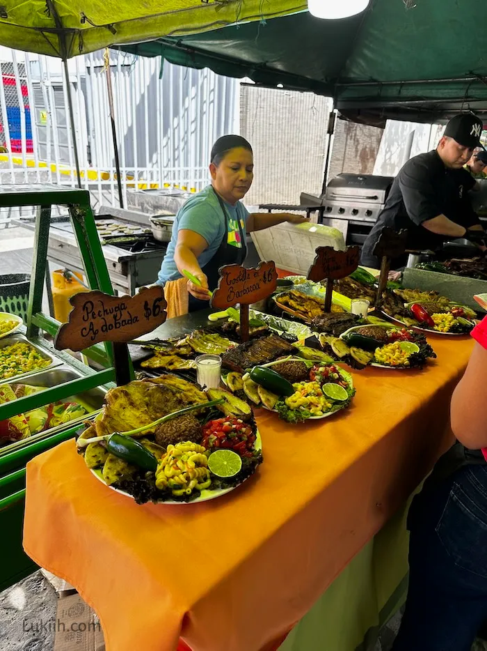 A food vendor with several platters of food displayed.