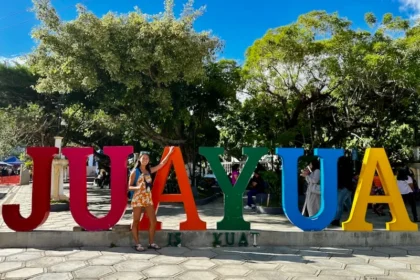 A woman standing next to a sign that says JUAYUA.