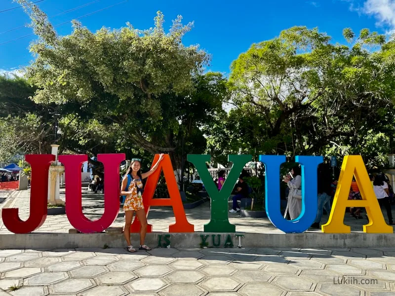 A woman standing next to a sign that says JUAYUA.