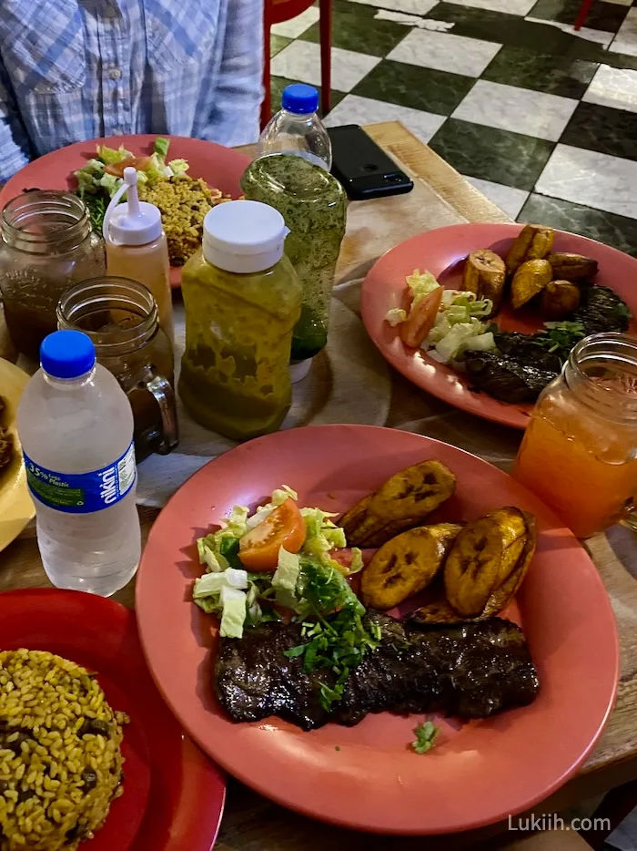 Several plates with steak, salad, and plaintain.