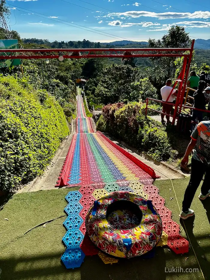 A tall rainbow slide with a tire for people to sit in.