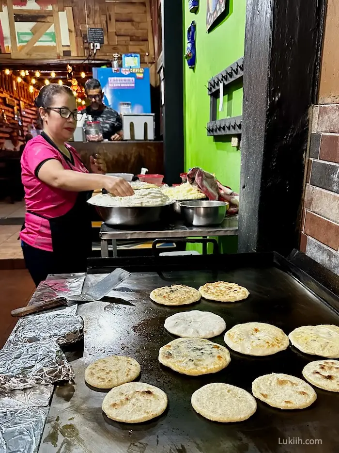 A woman grilling round corn cakes.