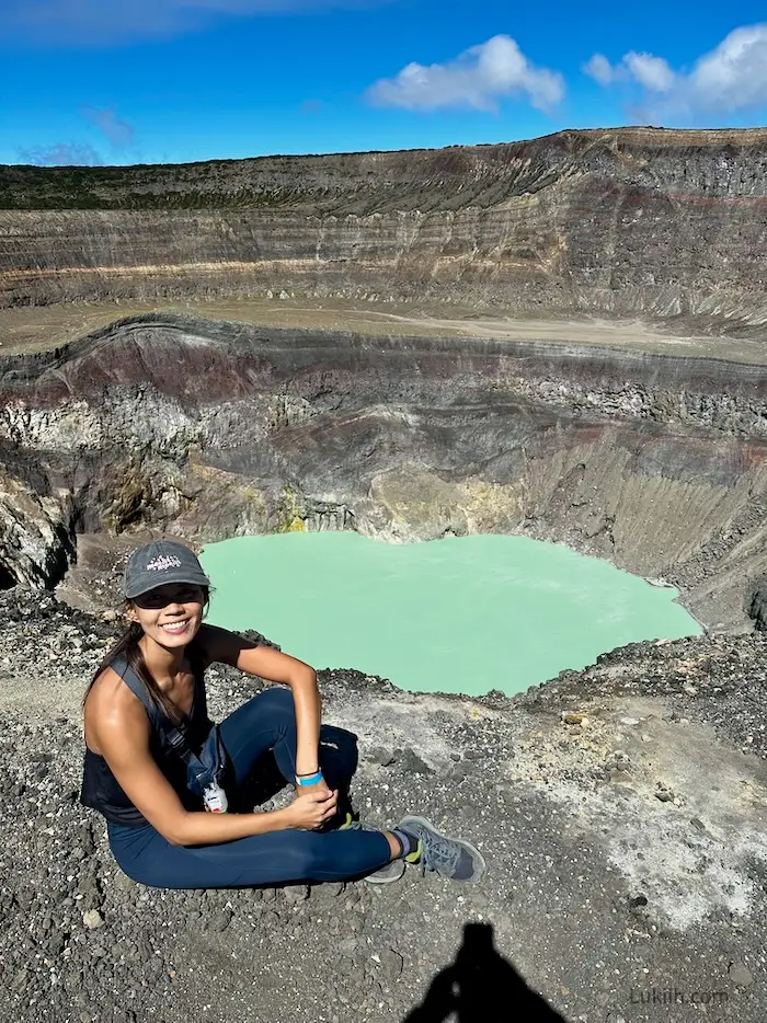 A woman sitting on the edge with a very turquoise lake in the background